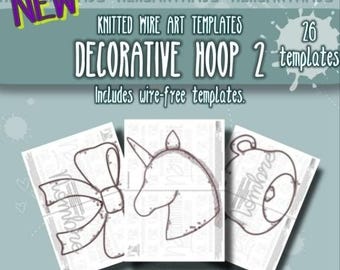May include: A set of 26 knitted wire art templates titled Decorative Hoop 2, featuring wire-free designs. The image displays three white paper sheets with black line drawings of a bow, a unicorn head, and a teapot on a blue background.