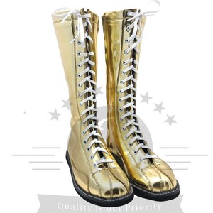 K&ouml;nnte beinhalten: Ein Paar goldfarbene, kniehohe Stiefel mit wei&szlig;en Schn&uuml;rsenkeln. Die Stiefel haben eine gl&auml;nzende, metallische Oberfl&auml;che und eine schwarze Sohle. Die Schn&uuml;rsenkel sind oben gebunden. Kost&uuml;m- oder Performance-Stiefel.