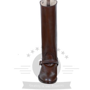 May include: Brown leather riding boots with a buckle strap and a pointed toe.