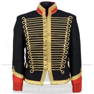 May include: A black military-style jacket with gold braid trim and red lining. The jacket has a stand-up collar and a button closure.