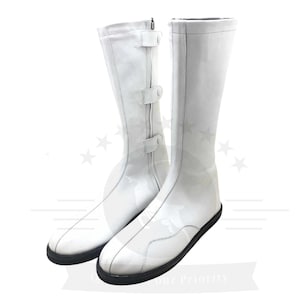 May include: A pair of white leather boots with buckles. The boots are knee-high and have a pointed toe.