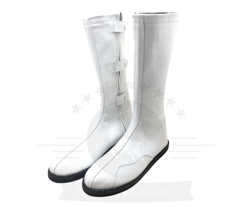 May include: A pair of white leather boots with buckles. The boots are knee-high and have a pointed toe.
