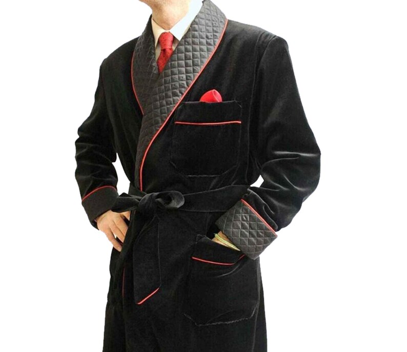 May include: A black velvet robe with a red trim and a quilted black lining. The robe has a shawl collar, a tie belt, and two pockets.