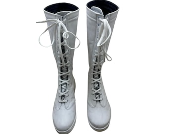 May include: A pair of white leather knee-high boots with lace-up closures.