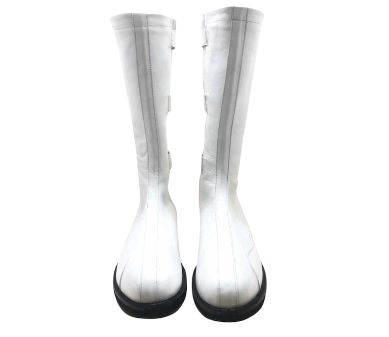 May include: A pair of white leather knee-high boots with black soles.