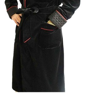 May include: A black velvet robe with red piping and a matching black velvet belt. The robe has a patch pocket on the left side.
