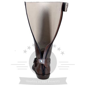 May include: Brown leather riding boots with a zipper up the back and a buckle on the side. The boots are folded down to show the lining.