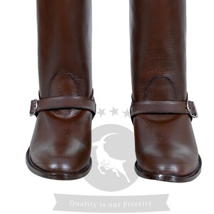 May include: A pair of brown leather riding boots with a buckle strap and a pointed toe.