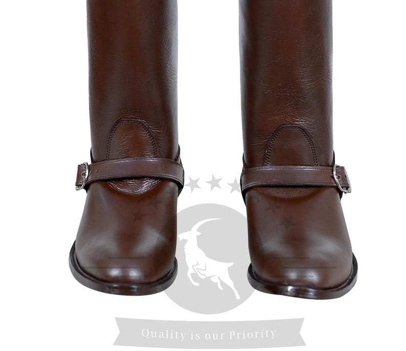 May include: A pair of brown leather riding boots with a buckle strap and a pointed toe.