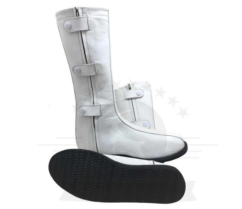 May include: White leather boots with a zipper and three white buttons on the side. The boots have a black rubber sole with a textured pattern.