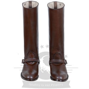 May include: A pair of brown leather riding boots with a buckle strap. The boots have a pointed toe and a tall shaft.