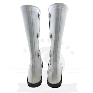 May include: A pair of white leather knee-high boots with black buckles and a black heel.