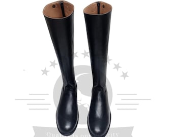 Puede incluir: Un par de botas de montar de cuero negro con una cremallera en la parte posterior de cada bota.