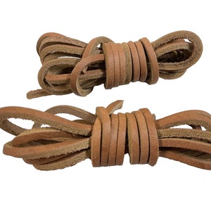 May include: Two bundles of light brown leather shoelaces, tightly coiled. The laces are made of thin strips of leather, and the ends are slightly frayed. The shoelaces are a neutral color and would complement a variety of shoe styles.