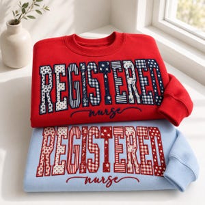 Könnte beinhalten: Ein rotes Sweatshirt mit dem Wort REGISTERED in gemusterten marineblauen und weißen Buchstaben und dem Wort nurse in Schreibschrift, auf einem hellblauen Sweatshirt mit REGISTERED in rot-weiß gemusterten Buchstaben und nurse in roter Schreibschrift.