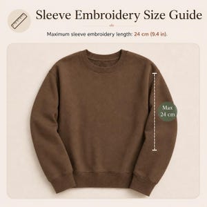 May include: A brown crewneck sweatshirt displayed with a size guide titled Sleeve Embroidery Size Guide. The graphic indicates a maximum sleeve embroidery length of 24 cm or 9.4 inches, shown with a dashed line along the sleeve of the garment.