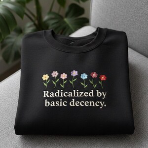 May include: A white ceramic mug with a black handle and the text "But First, Coffee" in a bold, black font. The mug is set against a neutral background, highlighting its simple design.