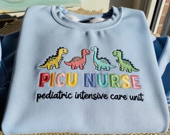 PICU Nurse Dinosaur Embroidered Sweatshirt: Pediatric Intensive Care Crewneck For Nurse