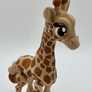 May include: A tan and brown giraffe figurine with large eyes and a friendly expression. The giraffe has brown spots on its body and a long neck. The figurine is standing on a white surface.