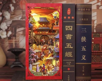 Könnte beinhalten: Ein 3D-Modell aus Holz einer chinesischen Stadtlandschaft mit einem roten Rahmen. Das Modell ist von innen beleuchtet und zeigt eine detaillierte Stadtlandschaft mit Gebäuden, Bergen und Figuren. Das Modell wird auf einem Regal neben zwei Büchern mit chinesischem Text präsentiert.
