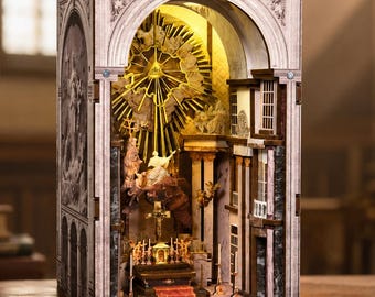 May include: A three-dimensional book nook insert featuring a detailed interior of a cathedral with arched architecture, a central altar, and a golden sunburst motif. The structure is illuminated from within, highlighting the intricate carvings.