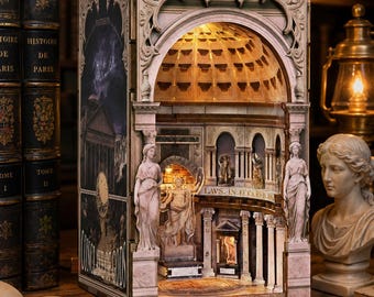 May include: A detailed book nook diorama depicting the interior of the Pantheon with illuminated coffered dome, classical columns, and miniature statues. The exterior side panel features a dark graphic print with the text Pantheon and Council of Gods.
