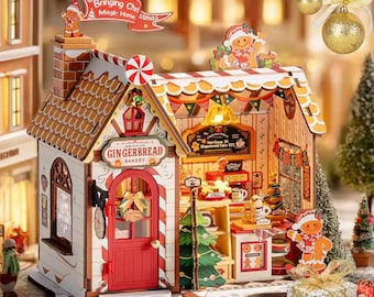 May include: A miniature gingerbread bakery with a red door and a sign that reads "Gingerbread Bakery." The roof is decorated with candy cane stripes and a chimney. A banner says "Bringing Christmas Magic Home Xmas."