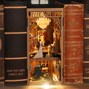 May include: A wooden book nook featuring a detailed interior scene with figures, a chandelier, and a piano. The book nook is nestled between two vintage-style books. The text "YOUR TEXT HERE SAMPLE TEXT" is visible on the side of the book.