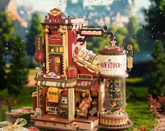 May include: A detailed wooden model of a factory with red and gold accents, featuring the text "Dream G Factory" and "Raw Stock". The model includes a Christmas tree inside a glass cylinder and the text "Shop Now For Christmas!"
