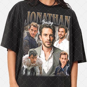 May include: Black t-shirt with a vintage-style graphic featuring the name "Jonathan Bailey" in gold lettering. The graphic also includes four images of the actor in different poses.