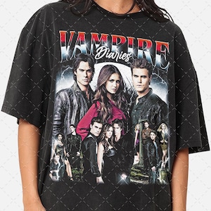 Puede incluir: Camiseta negra con un gráfico de estilo vintage del elenco de la serie de televisión "Vampire Diaries". El gráfico presenta el título del programa en letras rojas y blancas con las palabras "Diaries" en una fuente más pequeña. Los miembros del elenco se representan en grupo, con los personajes principales, incluidos Elena Gilbert, Damon Salvatore y Stefan Salvatore, destacados.