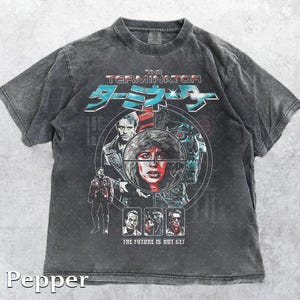 Könnte beinhalten: Pfefferfarbenes T-Shirt mit kurzen Ärmeln und einem Grafikdesign von "Terminator". Das Design enthält den Filmtitel in Englisch und Japanisch, zusammen mit Bildern von Charakteren und dem Text "THE FUTURE IS NOT SET."