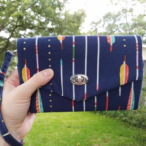 Portemonnaie mit Pfeilaufdruck auf marineblauem Hintergrund; Hält Handy, Kreditkarten und Bargeld, schließt mit Twist Lock