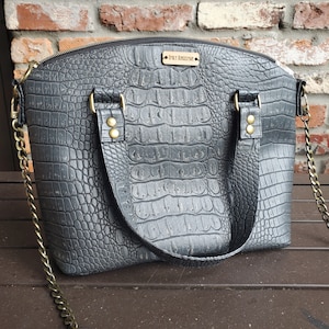 May include: A black crocodile embossed leather handbag with a gold chain strap and a gold nameplate that reads "Emily Ringeisen".