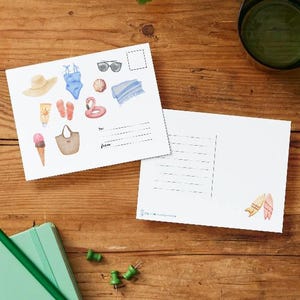 May include: A postcard featuring a watercolour illustration of assorted summer beach items, such as a swimsuit, sunglasses, a beach bag, flip flops, a beach towel, a flamingo float, a sun hat, sunscreen, and ice cream. The postcard has a blank space for writing a message and an address.