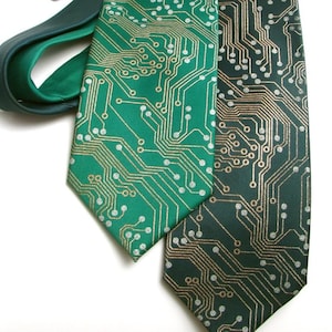 May include: Two neckties with a circuit board design. One tie is bright green with gold and silver accents, and the other is dark green with gold accents. The ties are made of a smooth, shiny fabric.