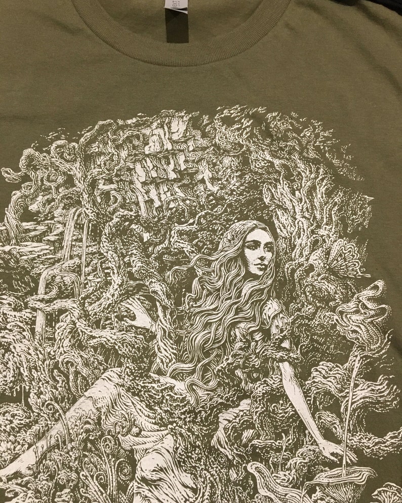 A detailed image of a long haired beautiful woman enveloped in branches, rocks, ferns and flowers printed on a mens shirt.