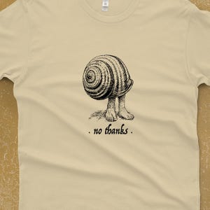 A Snail shell with human feet sticking out of the bottom. The caption reads "no thanks". It's printed with black ink on a cream shirt.