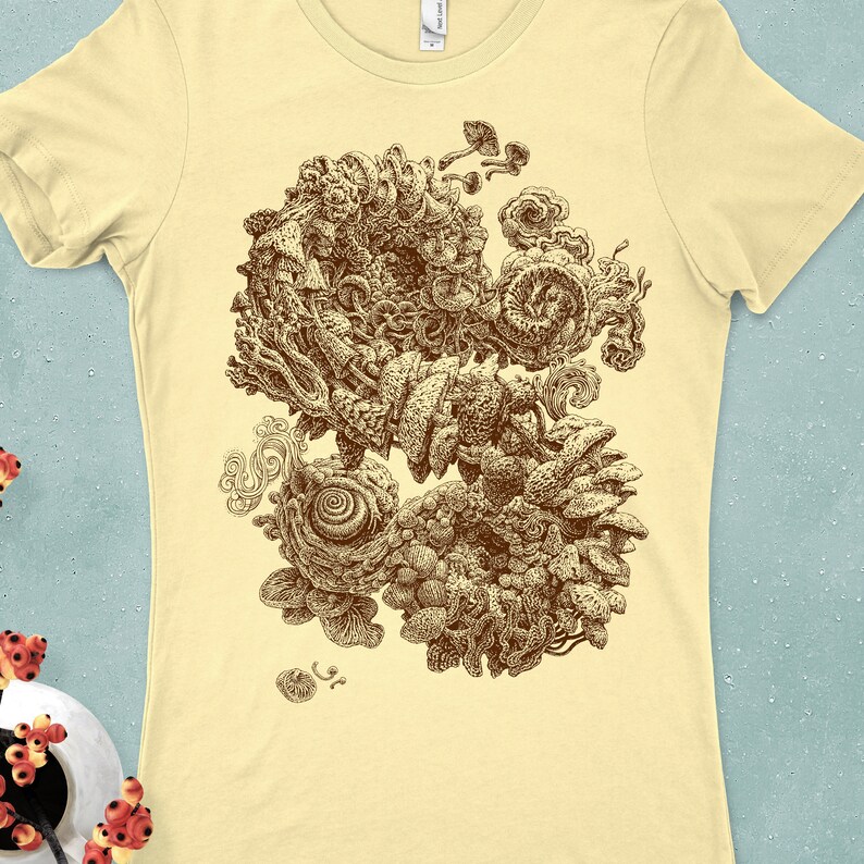 Op de afbeelding: Lichtgele t-shirt met een gedetailleerde bruine illustratie van een complex, organisch ontwerp. Het kunstwerk bevat wervelende patronen, paddenstoelachtige vormen en ingewikkelde texturen, waardoor een uniek grafisch t-shirt ontstaat.