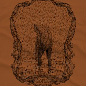 A funny frog drawing on a rust colored T-shirt