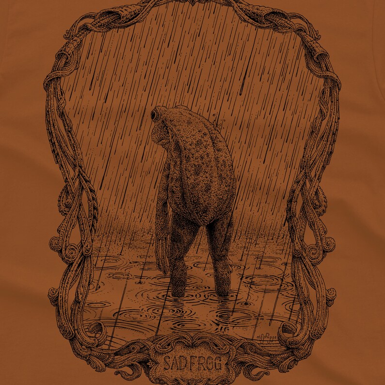 A funny frog drawing on a rust colored T-shirt
