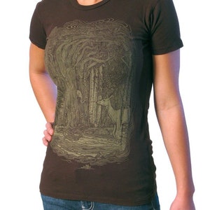 Puede incluir: Una camiseta marr&oacute;n con un estampado gr&aacute;fico verde y marr&oacute;n de una escena de bosque con un ciervo. El estampado gr&aacute;fico es detallado e intrincado.