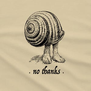 A Snail shell with human feet sticking out of the bottom. The caption reads "no thanks", as if to say the person doesn't want to come out of their shell. It's printed in black on a cream shirt.