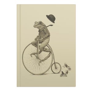 Peut inclure: Une illustration en noir et blanc d'une grenouille portant un chapeau et conduisant un vélo à grande roue. Trois petits insectes conduisent des vélos à l'arrière-plan.