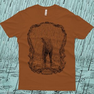 A drawing of a sad frog standing in the rain, surrounded by an ornate border. Screen printed onto a clay, Next Level brand T-shirt.