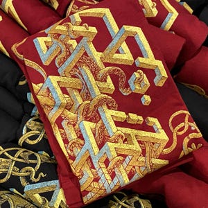 Screen printed graphic T-shirts in red and black with a yellow, gold and blue geometric pattern on it. There are tentacles weaving through the strange structure.