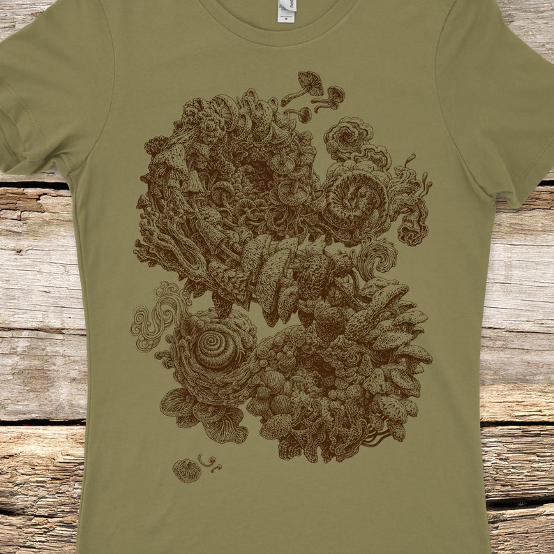 Op de afbeelding: Olijfgroen t-shirt met een gedetailleerde bruine illustratie van organische vormen, waaronder paddenstoelen en wervelende patronen. Het ontwerp is gecentreerd op het shirt, wat een opvallend visueel contrast cre&euml;ert.