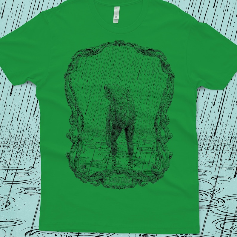 A detailed drawing of a sad frog standing in the rain, surrounded by an ornate border. Screen printed onto a green, Next Level brand T-shirt.