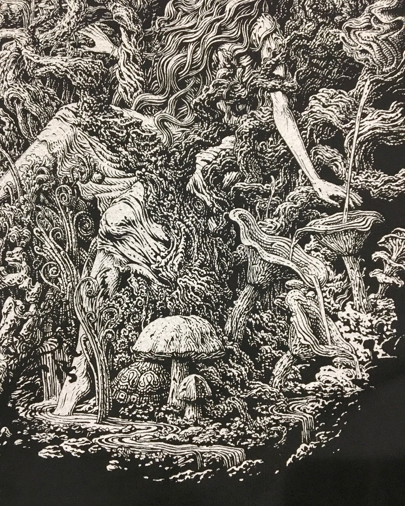 A woman dipping her toes in a small stream with a turtle and mushrooms on the shore on a tshirt.