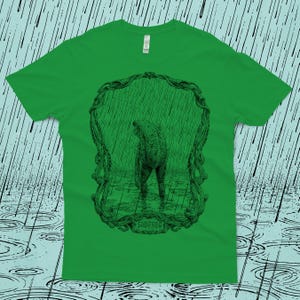 An original drawing of a sad frog standing in the rain, surrounded by an ornate border. Screen printed onto a Kelly green, Next Level brand T-shirt.